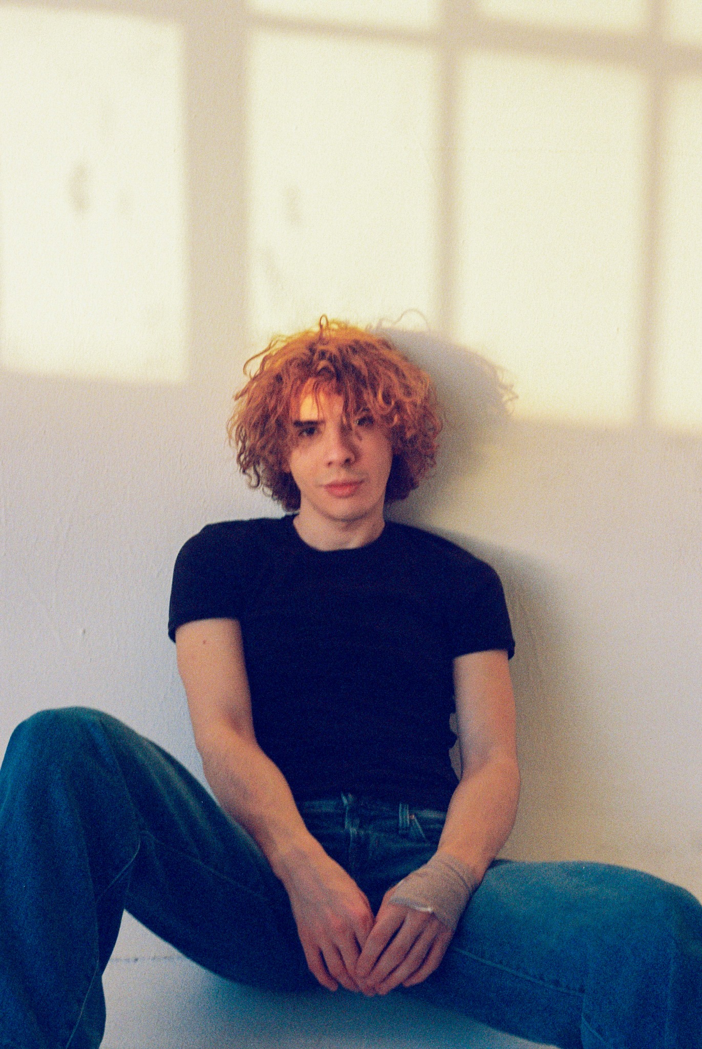 Caner Oz seated in jeans in warm window light