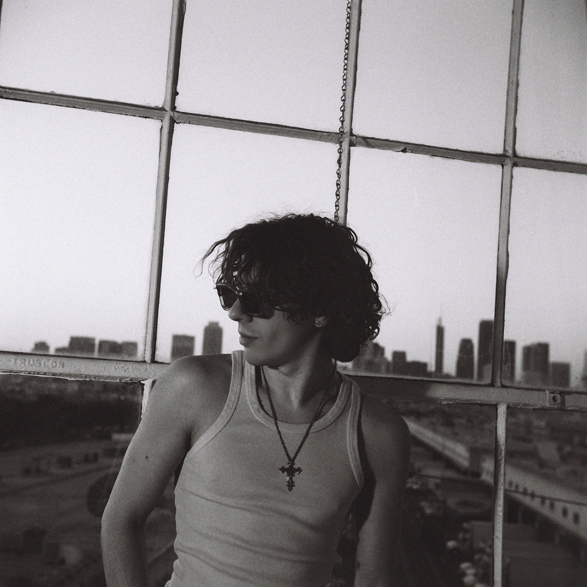 Black-and-white portrait of Caner Oz beside a studio window