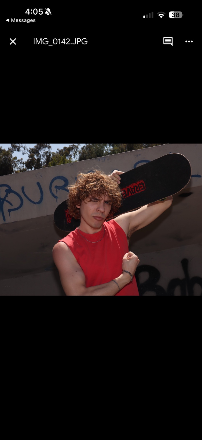 Caner Oz holding a skateboard behind his shoulders