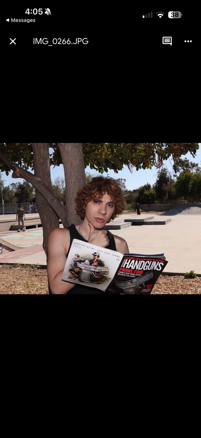 Caner Oz sitting by a tree with a magazine